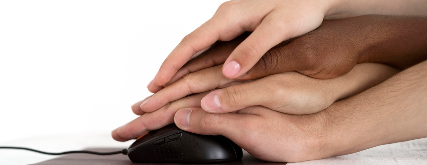 Manos de diferentes personas unidas sobre un ratón de computador, ilustrando la importancia de la accesibilidad digital universal