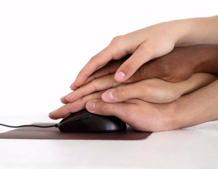 Manos de diferentes personas unidas sobre un ratón de computador, ilustrando la importancia de la accesibilidad digital universal